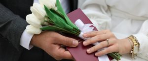 Newlyweds holding a white tulip bouquet and red marriage document at an ROM wedding in Singapore.