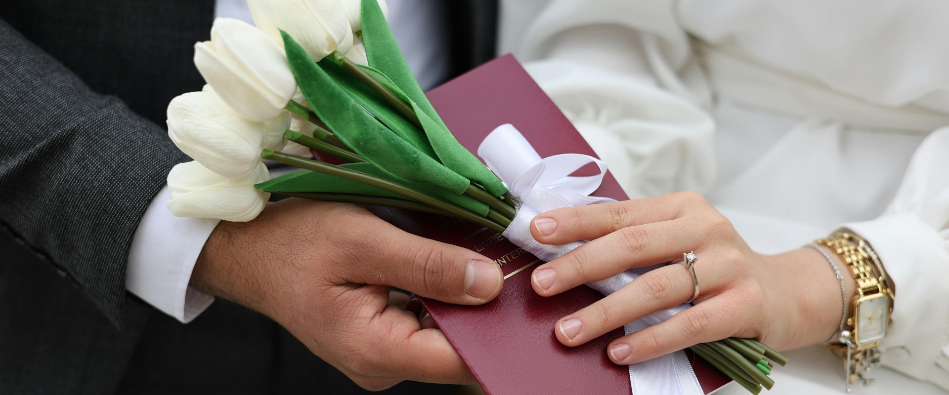 Newlyweds holding a white tulip bouquet and red marriage document at an ROM wedding in Singapore.