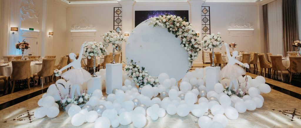 Luxury wedding photobooth in Singapore with white balloons and pastel floral arch setup in a ballroom.